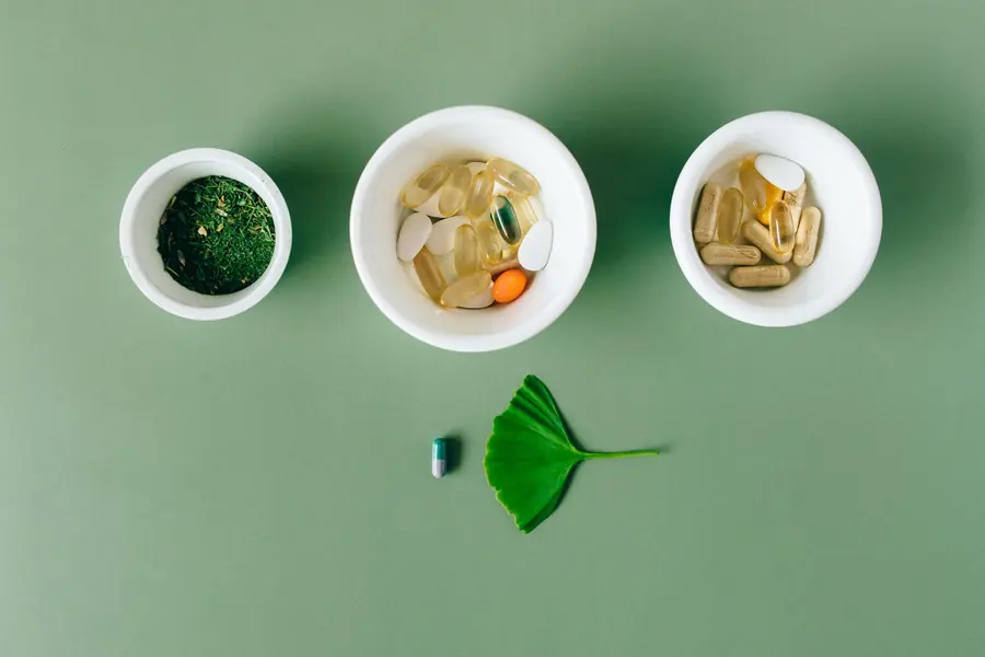 Herbal capsules and dried herbs in ceramic bowls