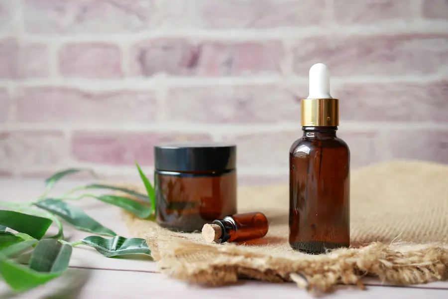 Essential oil in a glass bottle beside fresh eucalyptus