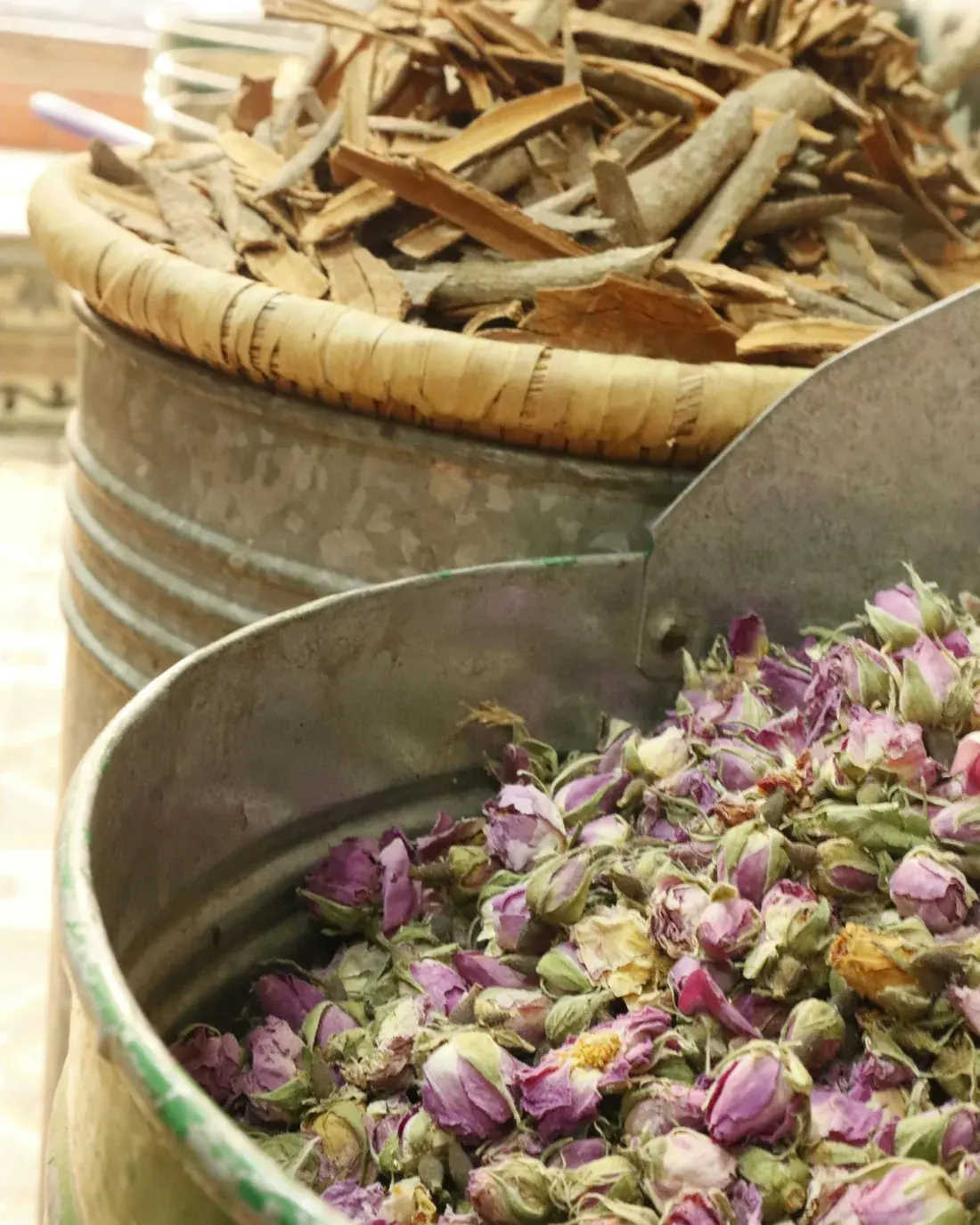 Dried rose buds and cinnamon bark in metal containers
